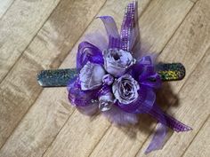 a purple corsage with flowers and sequins on the headband is sitting on a wooden floor