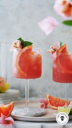 two glasses filled with watermelon margaritas on top of a white plate next to pink flowers