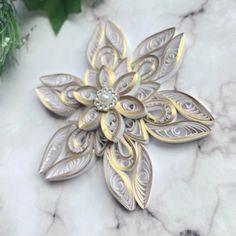 a white and gold flower brooch sitting on top of a marble table