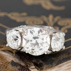 three stone diamond ring sitting on top of an old book