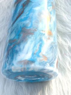 a blue and brown vase sitting on top of a white fur covered floor next to a window