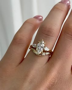 a woman's hand with a gold ring and two diamond engagement rings on it