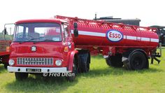 an old red truck is parked in the grass