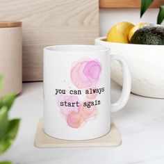 a coffee mug that says, you can always start again on the side next to some fruit