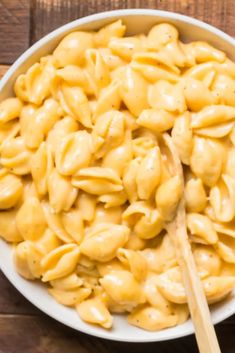 a white bowl filled with macaroni and cheese on top of a wooden table