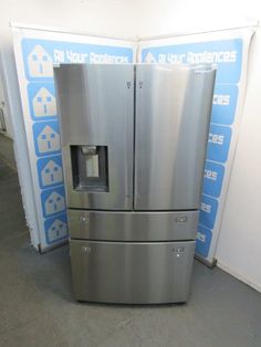 a stainless steel refrigerator in a room with blue and white signs on the wall behind it