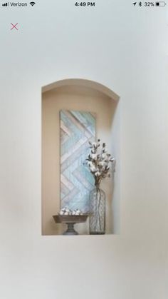 a vase filled with flowers sitting on top of a white wall next to a mirror