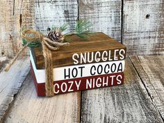 a wooden sign that says snuggles hot cocoa cozy nights on top of a book