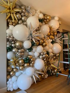 the balloon wall is decorated with gold, silver and white balloons