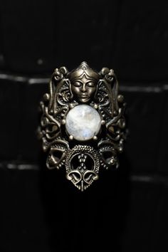 a silver ring with a white stone in the center and an ornate design around it