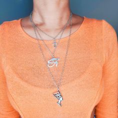 A trio of history, beauty, culture. The Silver Layered Egyptian Trio Charm Necklace features 3 of the most popular amulets of African Egyptian culture. It is perfect to wear with your favorite scoop neck blouse or turtleneck to truly display its beauty. The first layer features an Ankh charm, also known as an Egyptian cross. The second layer is the Eye of Horus charm. Associated with the moon, the Eye of Horus symbolizes good health, recovery and protection. Finally, all hail the queen, Nefertit Egyptian Cross, The Eye Of Horus, Scoop Neck Blouse, Beauty Culture, Egyptian Culture, Scoop Neck Blouses, Eye Of Horus, Amulets, Charm Necklace