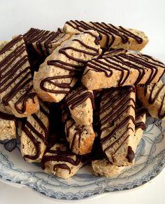 a plate full of cookies with chocolate drizzled on them