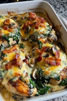 a casserole dish with chicken, spinach and bacon on top in a white baking dish