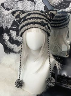 a white mannequin head wearing a black and white knitted hat with braids