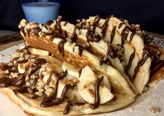 chocolate drizzled bananas on top of crepes with nuts and other toppings