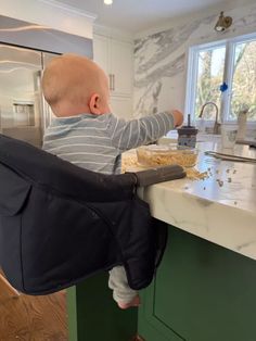 a baby sitting in a high chair at the kitchen counter