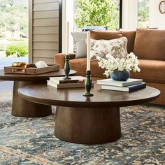 a living room with a couch, coffee table and books on the floor in front of a window