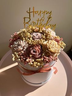 a birthday cake decorated with flowers on top of a white plate and gold lettering that says happy birthday