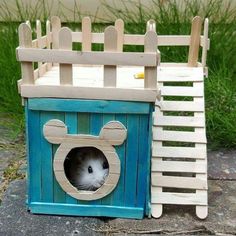 a wooden toy house with a hamster in it's hole on the ground