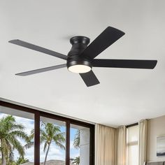 a ceiling fan in a living room with large windows