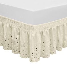 the bed skirt is made from white cotton and has an eyelet design on it