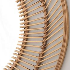 a circular mirror made out of bamboo sticks and wood strips on a white wall behind it