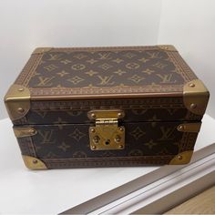 an old louis vuitton trunk sitting on top of a white counter next to a window