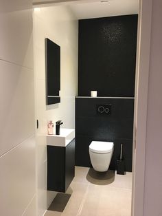 a white toilet sitting in a bathroom next to a black and white sink under a mirror