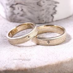 two wedding rings sitting on top of a marble slab