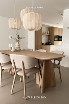 a dining room table with chairs and lights hanging from the ceiling