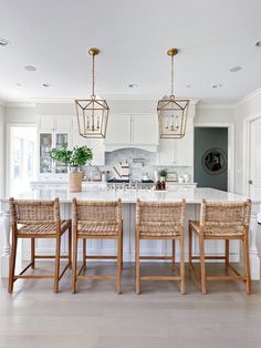 a kitchen with white cabinets and an island in the middle, surrounded by wicker chairs