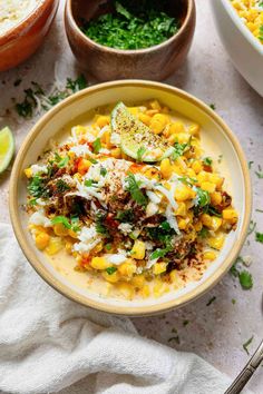 a bowl filled with mexican street corn and topped with sour cream, cilantro