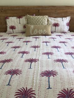 a bed with palm trees and love pillow on it