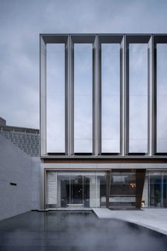 the exterior of a modern building with steam coming out of the ground and windows on each side