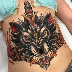 a woman with a tattoo on her stomach has an image of a wolf's head