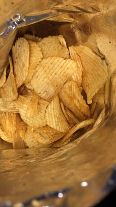 a metal bowl filled with potato chips on top of a table