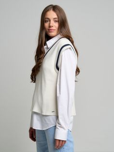 a woman is wearing a white sweater and jeans