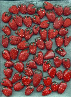 many red strawberries are scattered on a blue surface with white dots in the middle