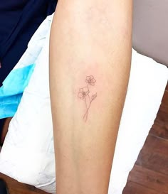 a woman's leg with a small flower tattoo on the left side of her arm