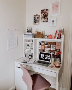 a white desk topped with a laptop computer next to a pink chair and framed pictures