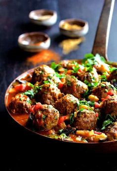 meatballs and vegetables are in a sauce on a plate with a spoon next to it