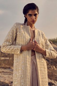 Champagne long trench jacket with all over sequin embellishments. Paired with an inner bralette with sequin work and draped juliet pant. - Aza Fashions Luxury Sequined Kurta With Traditional Drape, Luxury Sequined Dupatta With Traditional Drape, Fitted Beige Outerwear For Festive Season, Festive Fitted Beige Outerwear, Beige Long Sleeve Outerwear For Festive Occasions, Festive Beige Fitted Outerwear, Fall Wedding Long Coat, Spring Wedding Long Coat, Spring Wedding Long Coat Outerwear