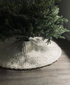 a crocheted pot holder with a pine tree in it on the wooden floor