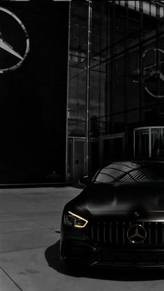 a black mercedes sports car parked in front of a building with the mercedes logo on it