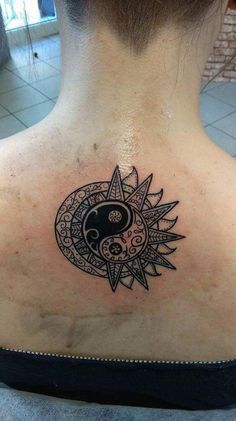 the back of a woman's neck with a yin - yang tattoo on it