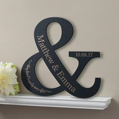 a couple's initials are placed on a shelf next to a vase with flowers