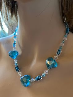 a woman wearing a necklace with blue glass beads and crystal stones on the back of her neck