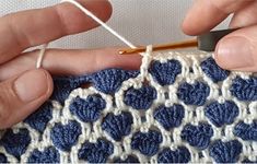 two hands are working on a crochet project, one is holding a knitting needle