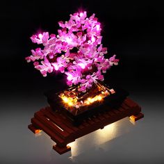 a purple flower arrangement is lit up on a wooden stand with small lights around it