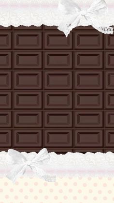 a chocolate bar with white bows on it's side and another piece of chocolate in the background